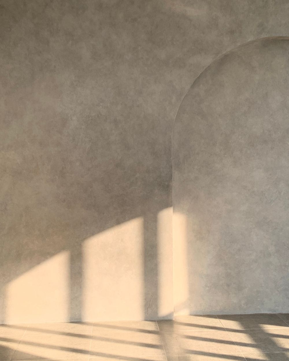 Un mur clair en forme d'arche, caressé par la lumière